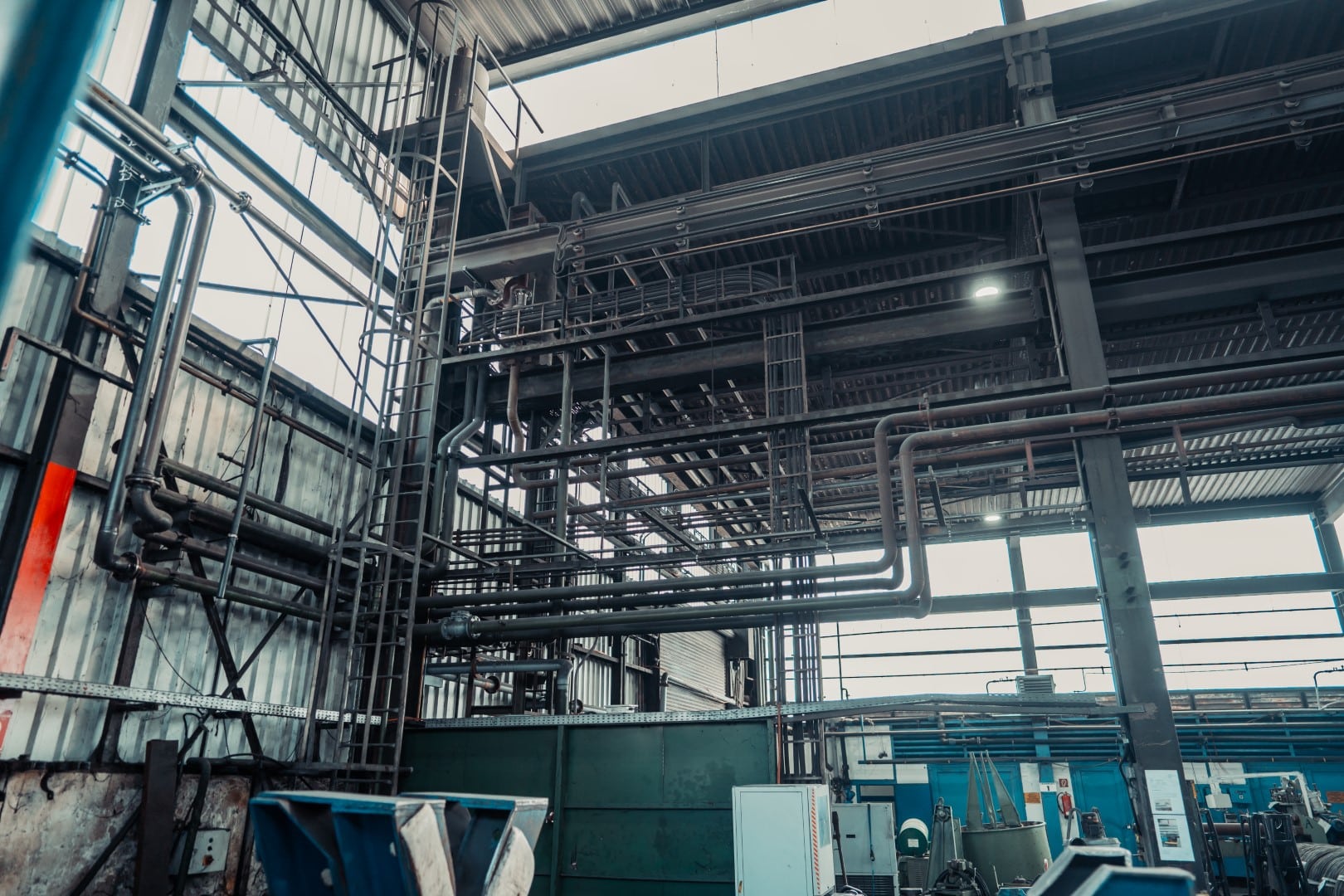 Stahlbau 10 Eine große Industriehalle im Stahlbau. Man sieht etliche auf mehreren Metern Höhe angebrachte Verrohrungen Leitern und Kabel. Das Ergebnis von gutem Rohrleitungsbau